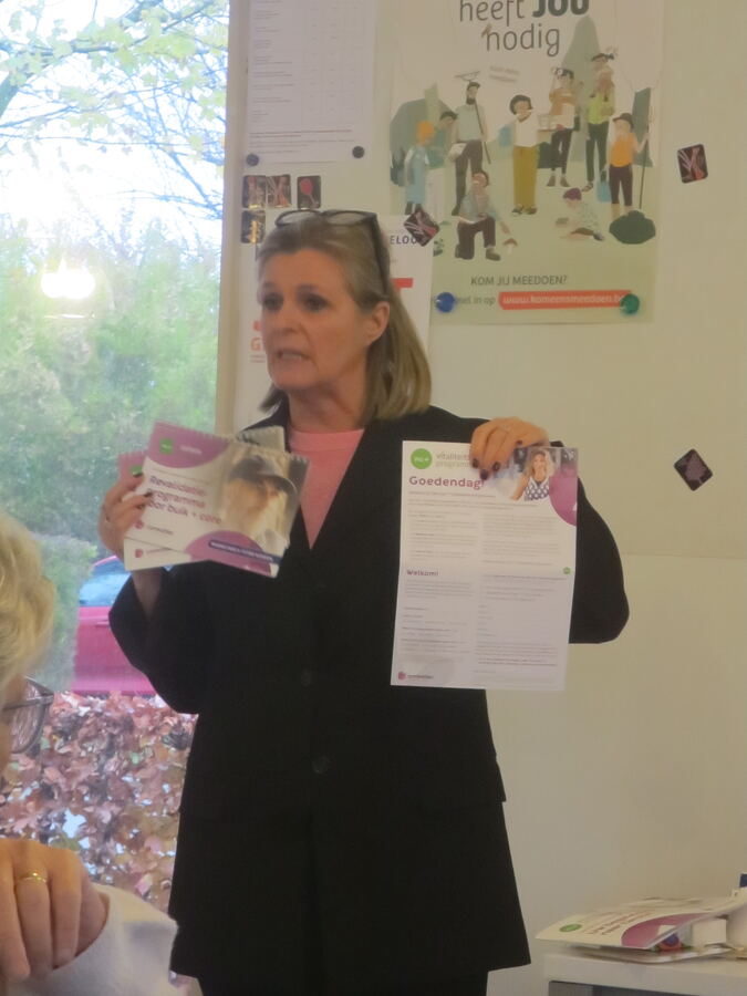 De spreker van Convatec toont brochures over het revalidatieprogramma en het vitaliteitsprogramma