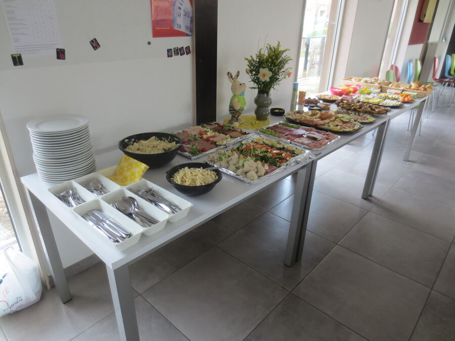 Het koud buffet met schotels vleeswaren, groenten, pasta en broodjes, met een paashaas en bloemen